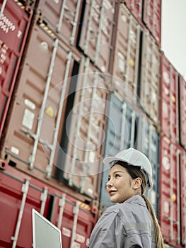 Asian woman worker holding Laptop and inspection container
