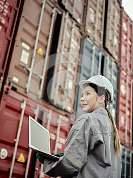 Asian woman worker holding Laptop and inspection container