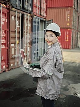 Asian woman worker holding Laptop and inspection container