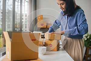 Asian woman worker or seller packing cardboard ecommerce shipping order box for dispatching