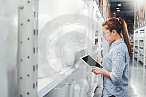 Asian woman worker working with digital tablet checking boxes Logistic import and export supplies packages in Warehouse ,