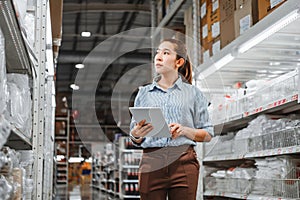Asian woman worker working with digital tablet checking boxes Logistic import and export supplies packages in Warehouse ,