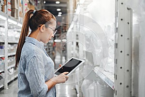 Asian woman worker working with digital tablet checking boxes Logistic import and export supplies packages in Warehouse ,