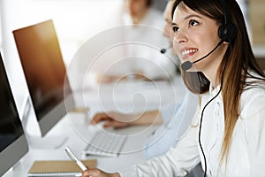 Asian woman working at customer service office. Business concept. Group of diverse operators at work in sunny call