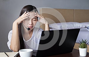 Asian woman working at home with headset making video conference with colleagues via laptop computer with stress emotion