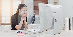 Asian woman is working from home. With illnesses with respiratory diseases Put on a medical mask, coughing in front of a computer