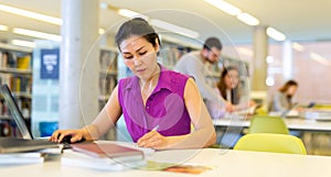 Asian woman working with laptop and books on science project in library