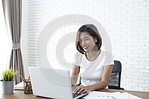 Asian woman working  laptop computer on wood desk in Home office