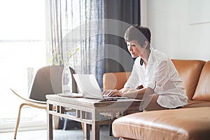 Asian woman working on laptop from home as freelancer