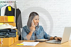 Asian woman working on laptop with talking smart phone