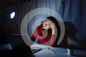 Asian woman working late at night with laptop computer home office looking screen monitor unhappy