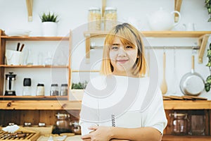 Asian woman write shopping lists in notepad by pen on her kitchen counter at home.