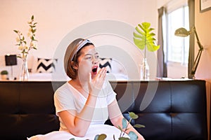 Asian woman yawning during on sofa and tired sleepy,Female with symptoms sleepiness