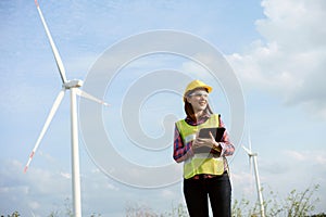 Asian woman in yellow helmet working with digital tablet at renewable energy farm. Female inspector controlling functioning of