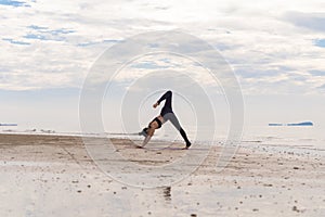 An Asian woman in yoga class club doing exercise and yoga at natural beach and sea coast outdoor in sport and recreation concept.