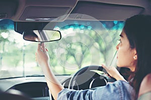 Asian women are adjusting the rearview mirror of the car