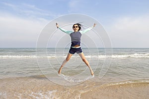 Asian women in bathing suits are jumping on the sand. Thai teenagers are playing at the beach during the daytime