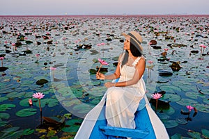 Asian women in a boat at the Red Lotus Sea full of pink flowers in Udon Thani Thailand.