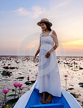 Asian women in a boat at the Red Lotus Sea Kumphawapi full of pink flowers in Udon Thani Thailand.