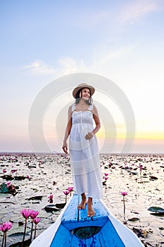 Asian women in a boat at the Red Lotus Sea Kumphawapi full of pink flowers in Udon Thani Thailand.