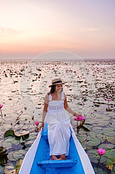 Asian women in a boat at the Red Lotus Sea Kumphawapi full of pink flowers in Udon Thani Thailand.