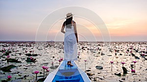 Asian women in a boat at the Red Lotus Sea Kumphawapi full of pink flowers in Udon Thani Thailand.