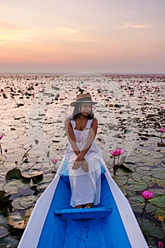 Asian women in a boat at the Red Lotus Sea Kumphawapi full of pink flowers in Udon Thani Thailand.