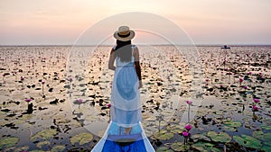 Asian women in a boat at the Red Lotus Sea Kumphawapi full of pink flowers in Udon Thani Thailand.