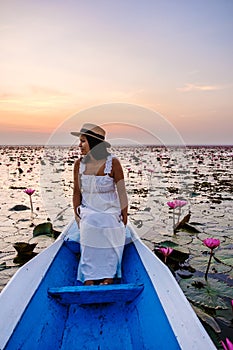 Asian women in a boat at the Red Lotus Sea Kumphawapi full of pink flowers in Udon Thani Thailand.