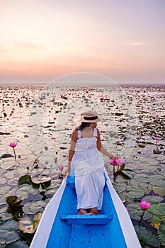 Asian women in a boat at the Red Lotus Sea Kumphawapi full of pink flowers in Udon Thani Thailand.