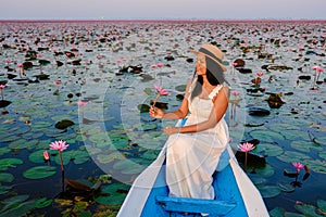 Asian women in a boat at the Red Lotus Sea Kumphawapi full of pink flowers in Udon Thani Thailand.