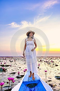 Asian women in a boat at the Red Lotus Sea Kumphawapi full of pink flowers in Udon Thani Thailand.