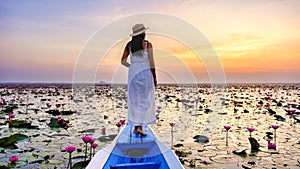 Asian women in a boat at the Red Lotus Sea Kumphawapi full of pink flowers in Udon Thani Thailand.