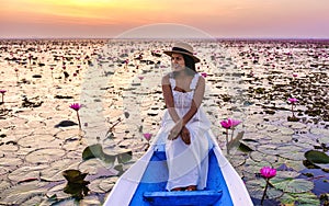 Asian women in a boat at the Red Lotus Sea Kumphawapi full of pink flowers in Udon Thani Thailand.