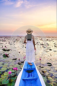 Asian women in a boat at the Red Lotus Sea Kumphawapi full of pink flowers in Udon Thani Thailand.