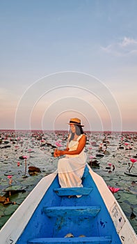 Asian women in a boat at the Red Lotus Sea Kumphawapi full of pink flowers in Udon Thani Thailand.