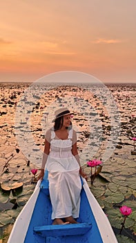 Asian women in a boat at the Red Lotus Sea Kumphawapi full of pink flowers in Udon Thani Thailand.