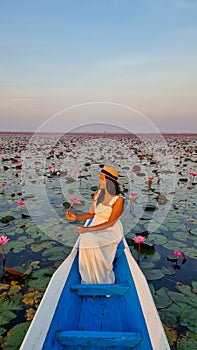 Asian women in a boat at the Red Lotus Sea Kumphawapi full of pink flowers in Udon Thani Thailand.