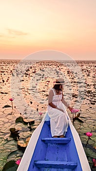 Asian women in a boat at the Red Lotus Sea Kumphawapi full of pink flowers in Udon Thani Thailand.