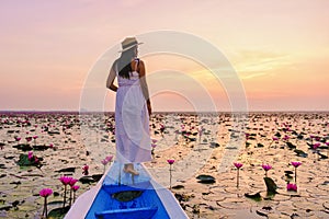 Asian women in a boat at the Red Lotus Sea Kumphawapi full of pink flowers in Udon Thani Thailand.