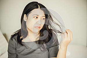 Asian women bore and moody with damaged hair and split ends due to lack of nourishment