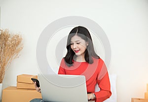 Asian women buying goods online through computer and cell phone