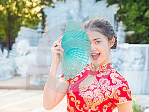 Asian women in Chinese national costumes hold wooden fan for the Chinese New Year