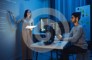 asian woman developers collaborating on a coding project, with one member presentation at code projected on the wall while the