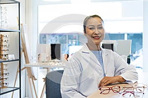 Asian women Doctor optometrist smiling while using tablet and recommend customer to choose glasses beautiful frame trial inside of