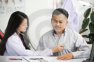 Asian women Doctor using stethoscope for examining patient  in his office at Hospitals photo