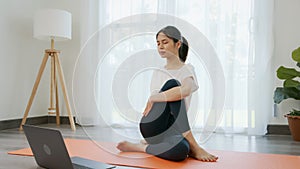 Asian women doing yoga exercises by themselves and watch video tutorials online from the laptop.