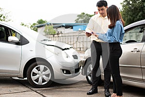 Asian women driver Talk to Insurance Agent for examining damaged car and customer checking on report claim form after an accident