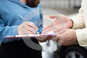 Asian women driver Talk to Insurance Agent for examining damaged car and customer checking on report claim form after an accident