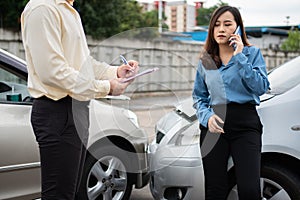 Asian women driver Talk to Insurance Agent for examining damaged car and customer checking on report claim form after an accident